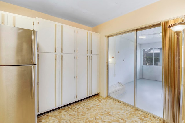 interior space with white cabinets and stainless steel fridge