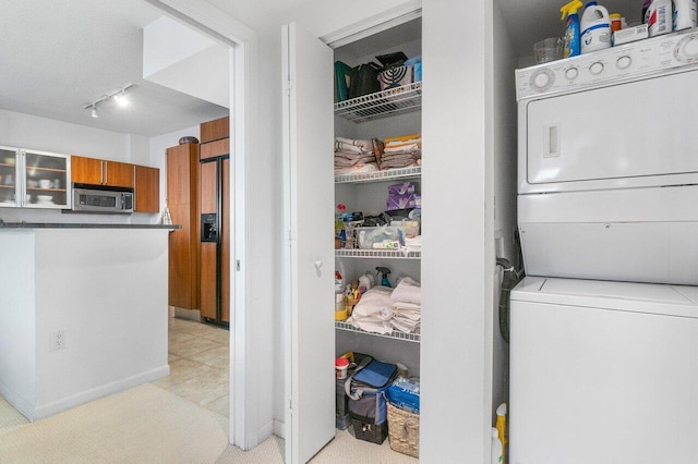 laundry room with stacked washer / drying machine and track lighting