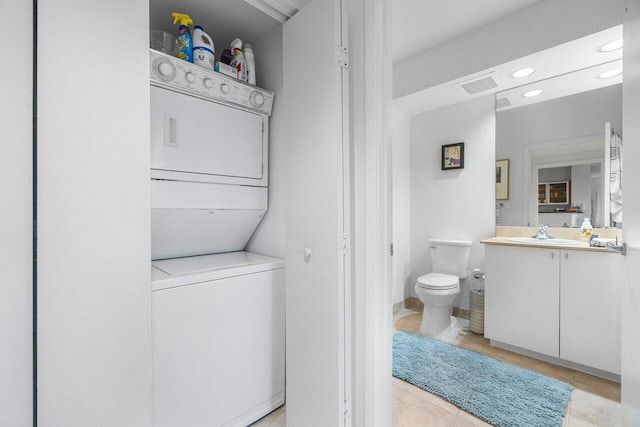 bathroom featuring vanity, tile patterned floors, toilet, and stacked washing maching and dryer