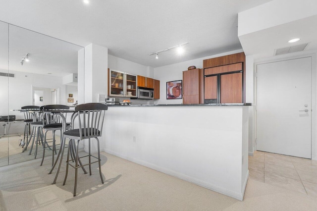 kitchen with track lighting, kitchen peninsula, and light carpet