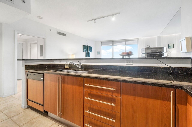 kitchen featuring dishwasher, sink, light tile patterned floors, and dark stone counters