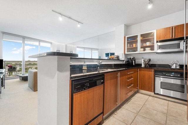 kitchen with light tile patterned flooring, appliances with stainless steel finishes, kitchen peninsula, and dark stone countertops