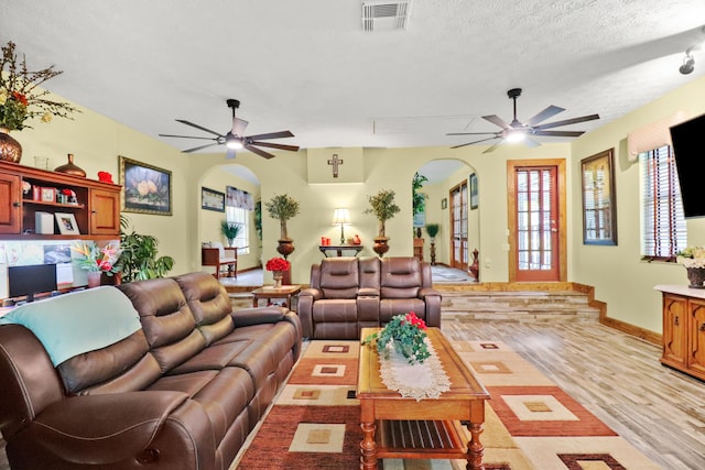 living room featuring ceiling fan, light hardwood / wood-style floors, and a textured ceiling