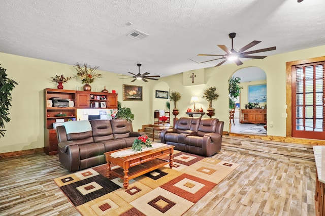 living room with ceiling fan, a textured ceiling, and light hardwood / wood-style flooring