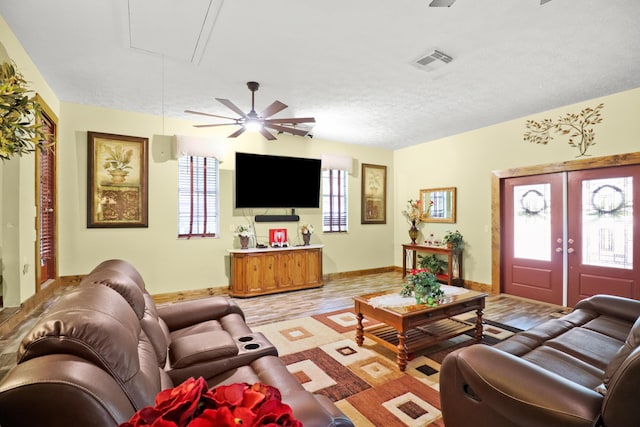 living room featuring light wood-style flooring, visible vents, baseboards, french doors, and attic access