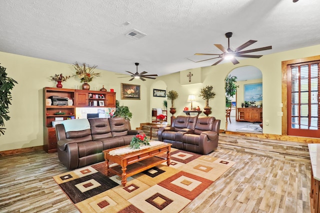 living area featuring a textured ceiling, light wood-type flooring, visible vents, and a ceiling fan