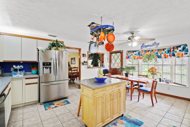 kitchen with light tile patterned flooring, a center island, ceiling fan, a textured ceiling, and stainless steel fridge with ice dispenser