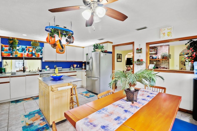 kitchen featuring light tile patterned floors, stainless steel refrigerator with ice dispenser, visible vents, and white cabinets