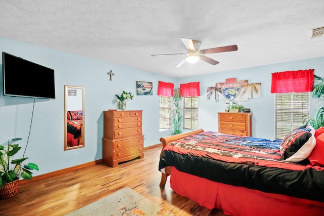 bedroom with hardwood / wood-style flooring, a textured ceiling, and ceiling fan