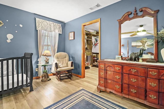 bedroom featuring baseboards, visible vents, wood finished floors, a walk in closet, and a closet