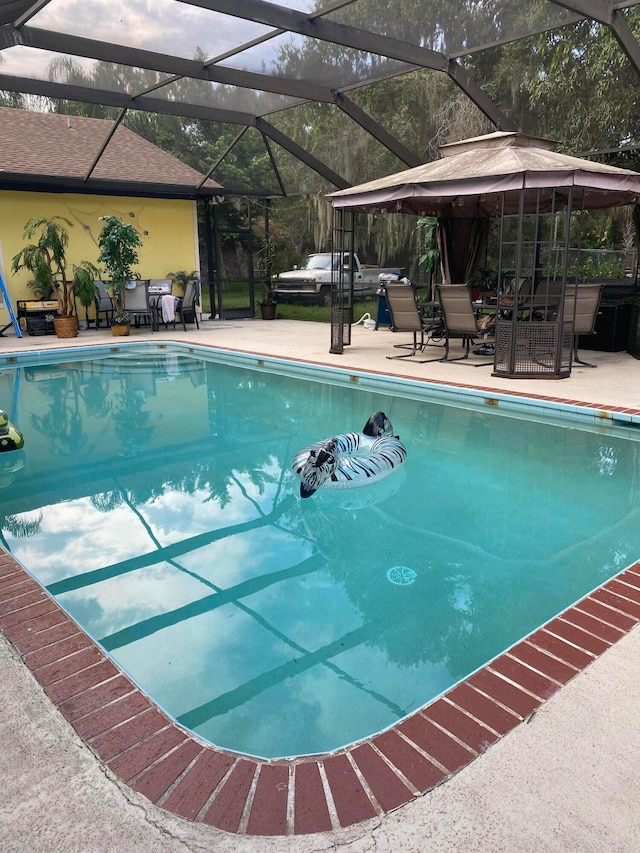 view of swimming pool featuring glass enclosure and a patio area