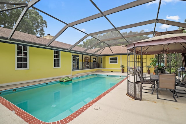 view of swimming pool featuring glass enclosure and a patio