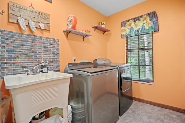 clothes washing area featuring sink, washer and dryer, and light tile patterned flooring