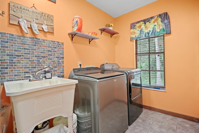 laundry area featuring light tile patterned floors, laundry area, a sink, baseboards, and washer and clothes dryer