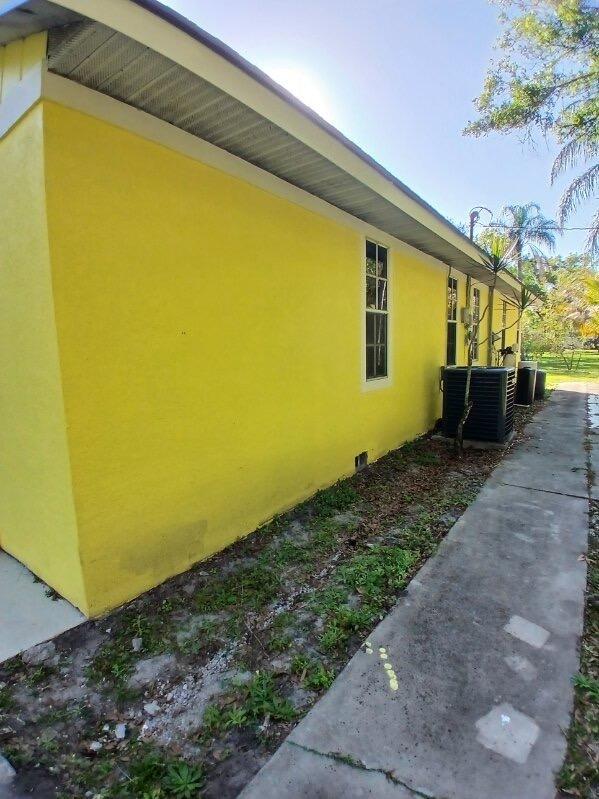 view of side of property with central AC unit and stucco siding