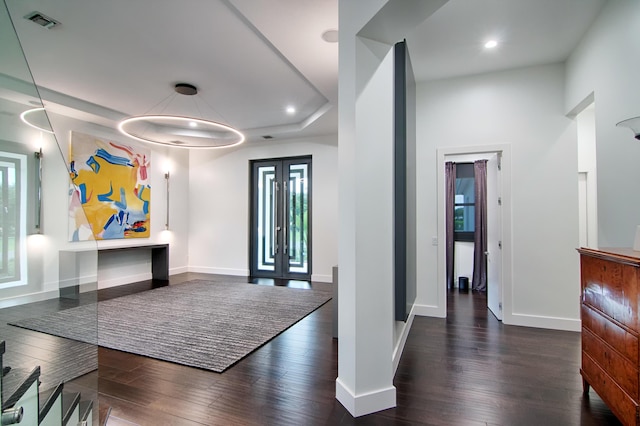 entrance foyer featuring french doors, a tray ceiling, and dark wood-type flooring