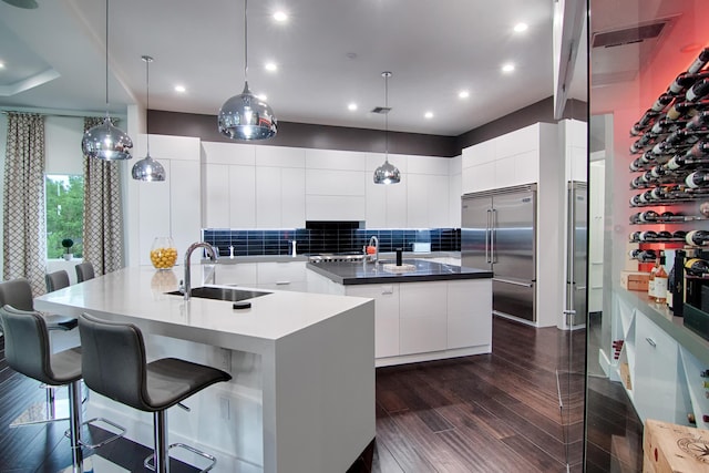 kitchen featuring built in refrigerator, a large island, sink, and white cabinets