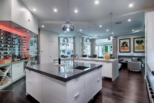 kitchen featuring a large island, sink, dark wood-type flooring, pendant lighting, and white cabinets