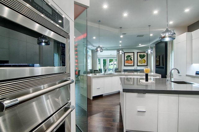 kitchen with pendant lighting, white cabinetry, sink, and stainless steel double oven