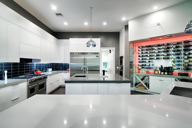 kitchen featuring premium appliances, white cabinetry, hanging light fixtures, and sink