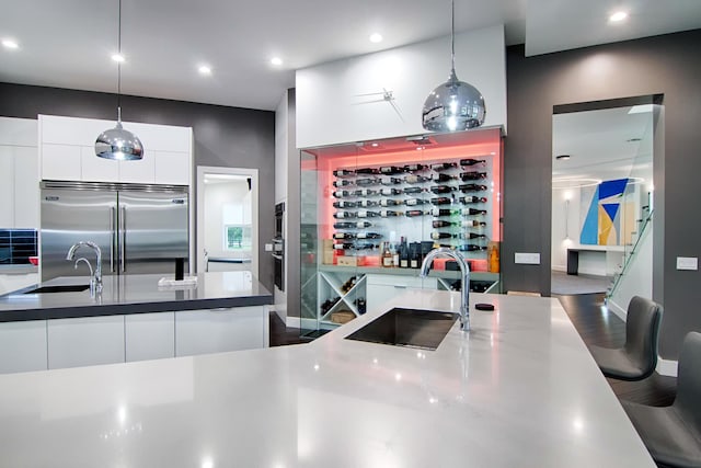 kitchen with white cabinets, pendant lighting, built in fridge, and sink