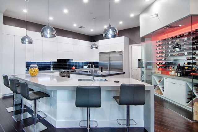 kitchen featuring pendant lighting, premium appliances, sink, and a breakfast bar