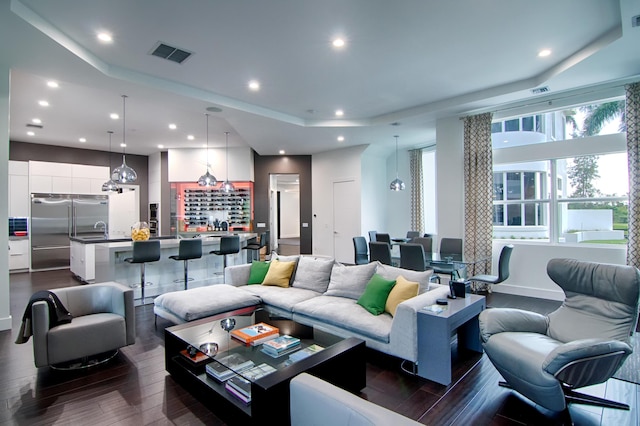 living room with a tray ceiling and dark hardwood / wood-style floors