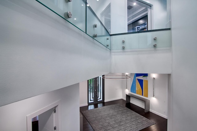 interior space featuring a towering ceiling and dark wood-type flooring