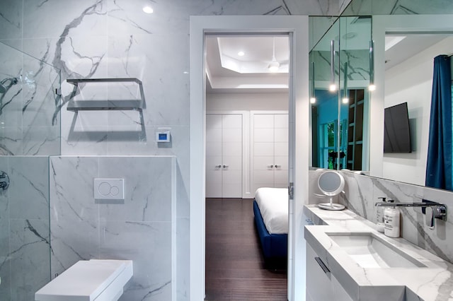 bathroom with vanity, a raised ceiling, decorative backsplash, and tile walls