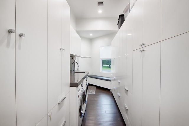 kitchen with white cabinets, washing machine and dryer, dark wood-type flooring, and sink