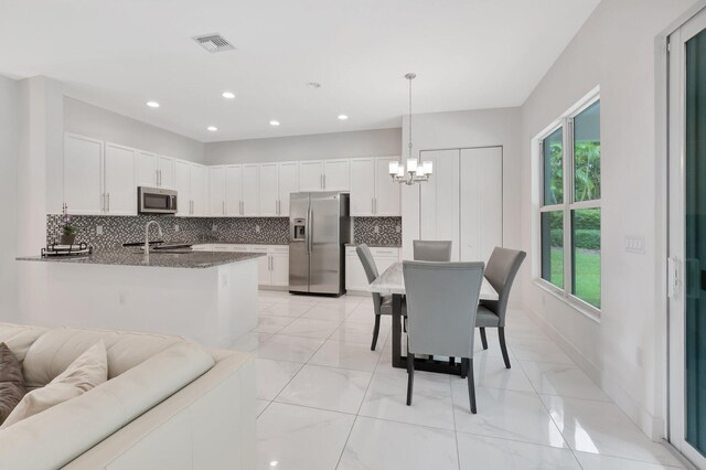 kitchen with appliances with stainless steel finishes, decorative backsplash, white cabinets, and a healthy amount of sunlight