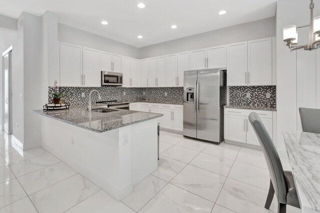 kitchen with appliances with stainless steel finishes, white cabinets, light stone counters, and tasteful backsplash