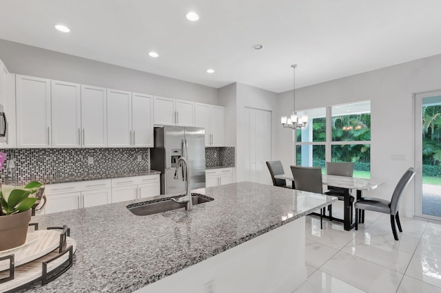 kitchen featuring stainless steel appliances, a notable chandelier, stone countertops, sink, and tasteful backsplash