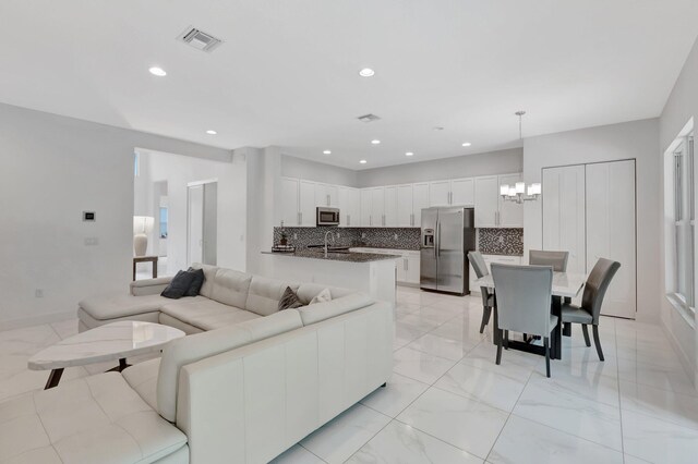 living room featuring light tile patterned flooring, sink, and a chandelier