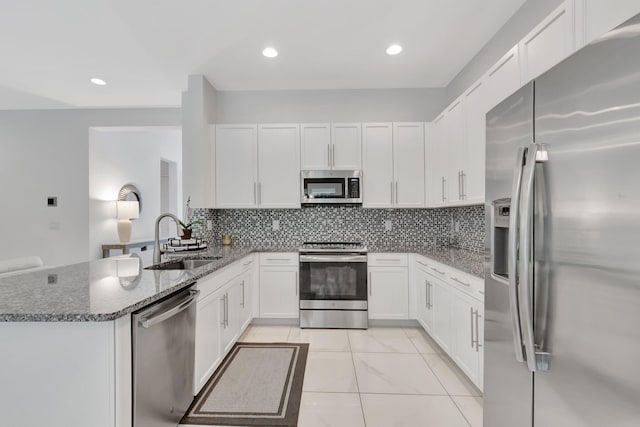 kitchen featuring appliances with stainless steel finishes, sink, tasteful backsplash, and kitchen peninsula