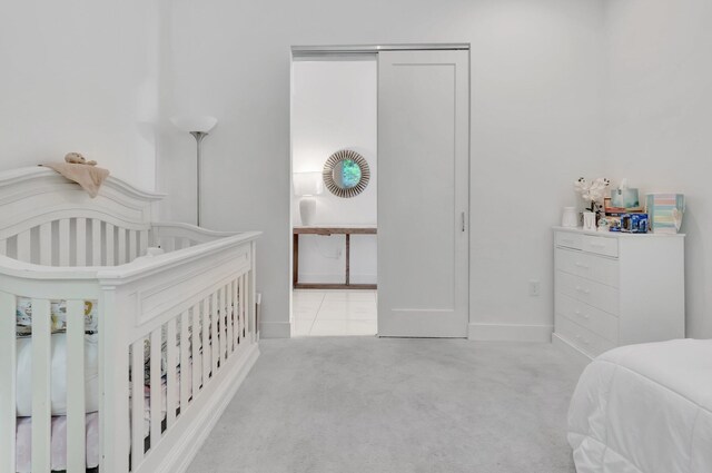 carpeted bedroom featuring a nursery area and a closet