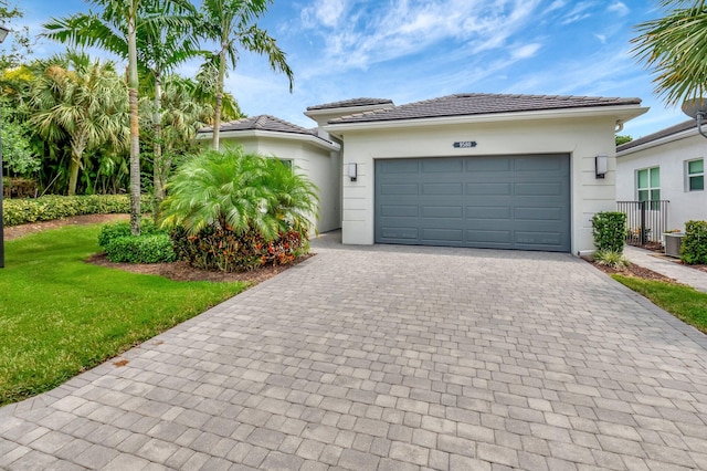 view of front of property featuring a front lawn, cooling unit, and a garage