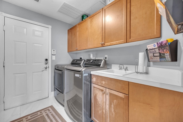 washroom featuring sink, washing machine and clothes dryer, light tile patterned floors, and cabinets