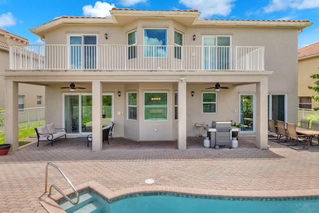 rear view of property featuring ceiling fan, a fenced in pool, a patio area, and a balcony