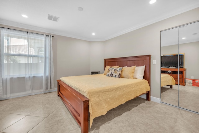 bedroom featuring light tile patterned flooring, crown molding, and a closet