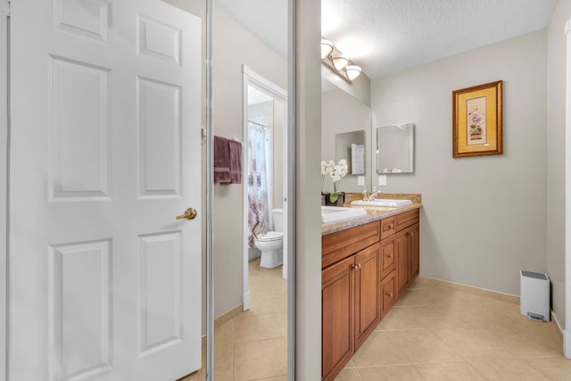 bathroom featuring tile patterned flooring, a textured ceiling, vanity, and toilet