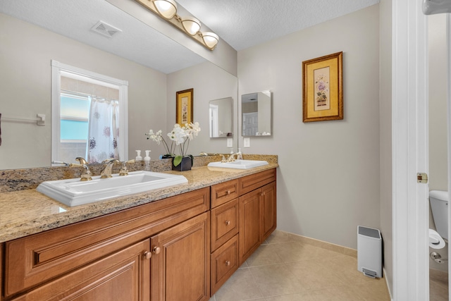 bathroom featuring tile patterned flooring, toilet, a textured ceiling, and vanity