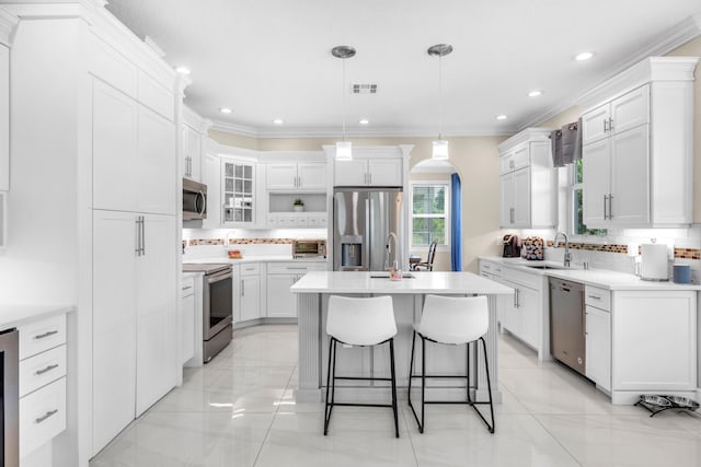9229 Delemar Ct, Wellington, FL 33414 - kitchen with appliances with stainless steel finishes, arched walkways, tasteful backsplash, ornamental molding, and an island with sink