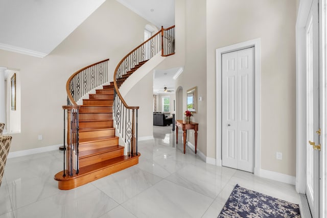 tiled foyer featuring ceiling fan, ornamental molding, and a towering ceiling