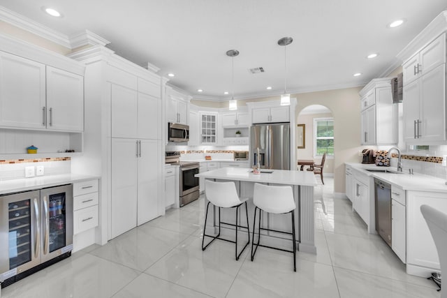 9229 Delemar Ct, Wellington, FL 33414 - kitchen with stainless steel appliances, a sink, wine cooler, arched walkways, and tasteful backsplash