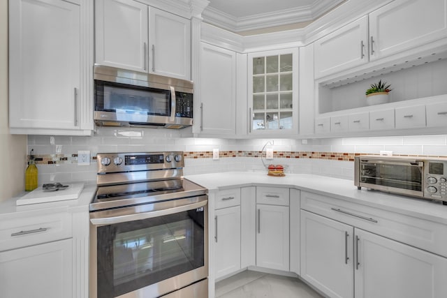 9229 Delemar Ct, Wellington, FL 33414 - kitchen featuring stainless steel appliances, white cabinets, light countertops, backsplash, and ornamental molding