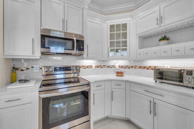 kitchen with backsplash, crown molding, stainless steel appliances, and white cabinets