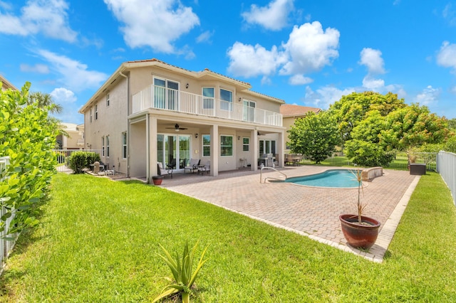 back of property featuring ceiling fan, a patio, a balcony, a fenced in pool, and a lawn