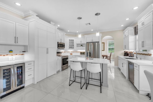 kitchen with backsplash, white cabinets, wine cooler, sink, and stainless steel appliances