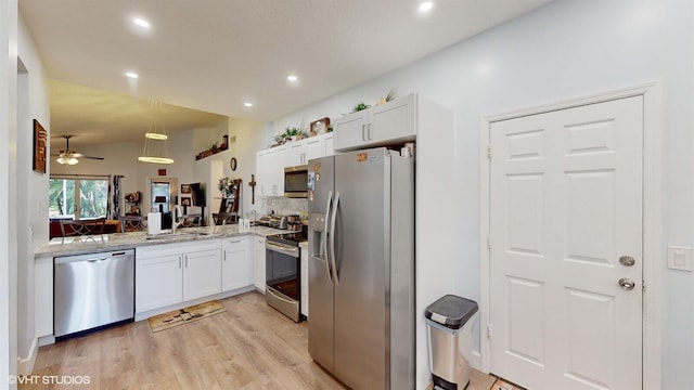 kitchen featuring lofted ceiling, appliances with stainless steel finishes, light stone counters, white cabinetry, and a sink